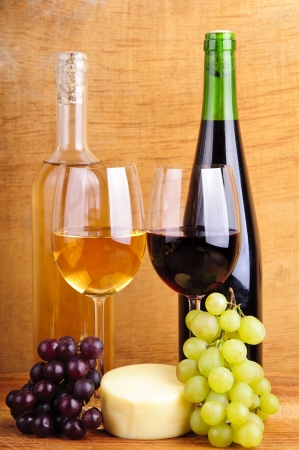 still life with cheese, wine and grapes on a vintage wooden backgroundの写真素材