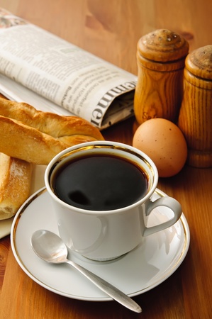 breakfast with cup of coffee and newspaper, croissant, egg, salt, pepperの写真素材