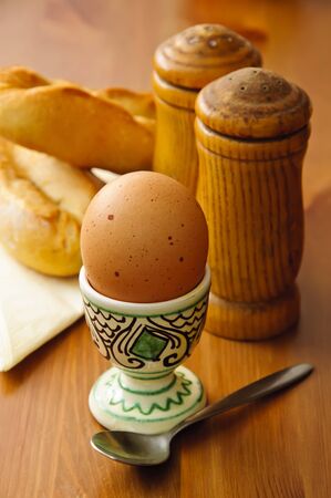breakfast egg with salt, pepper and bread on a wooden backgroundの写真素材