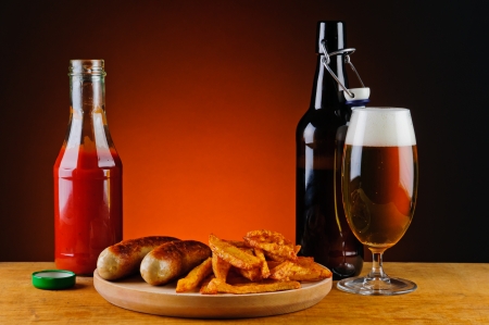 still life with grilled sausages, french fries, ketchup and beerの写真素材