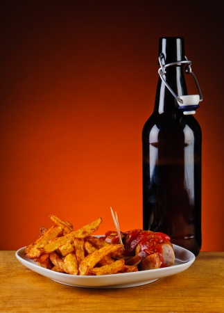 curry sausages with french fries and bottle of beerの写真素材