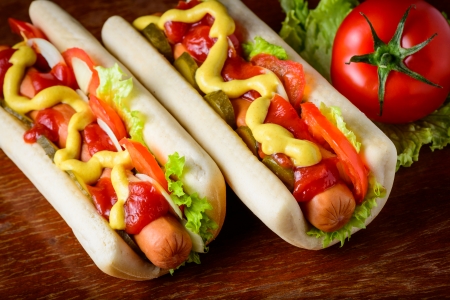 two traditional homemade hotdogs with fresh vegetables on a tableの写真素材