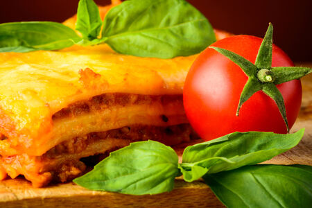traditional homemade lasagna bolognese closeup with basil and tomatoの写真素材