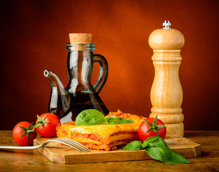 traditional dinner with lasagna bolognese, olive oil and pepper millの写真素材