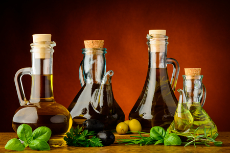 different bottles of infused olive oil with fresh green herbsの写真素材