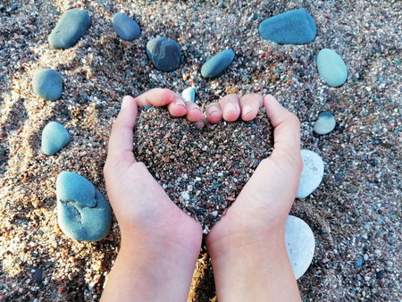 The girl is holding heart-shaped pebbles and sand in her hands. Summertime, travel and vacation. Montenegro, Beciciの写真素材