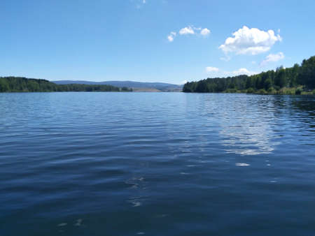 View of a calm blue mountain lake. Wonderful landscape. In the background are sky, clouds, forest and hills. Vlasina Lake, Serbiaの写真素材