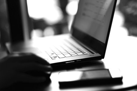 Close up view of laptop and mobile phone with freelancer working on it. Dark tone. Business working...