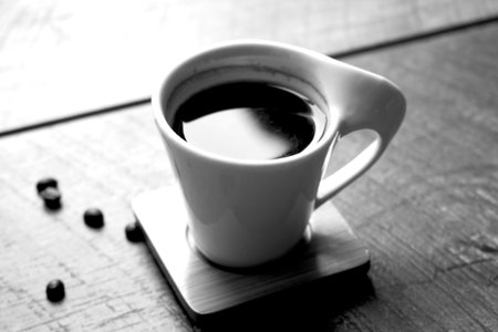 Black and white small coffee cup of expresso with beans. Artistic concept