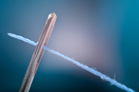Macro view of thread going through the eye of a needle 