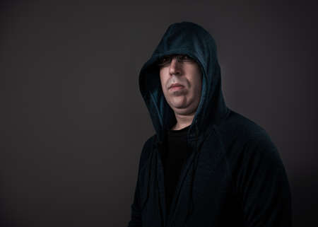 A man in his 30's wearing a hoodie shot against a grey background.の写真素材