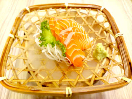 fresh sashimi salmon with wasabi and lettuce served in a woven rattan dishの写真素材