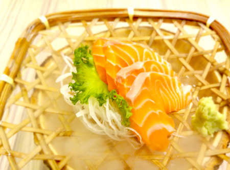 fresh sashimi salmon with wasabi and lettuce served in a woven rattan dishの写真素材