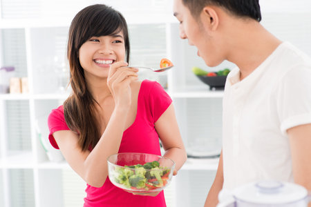 Guy trying the salad prepared by his girlfriendの写真素材