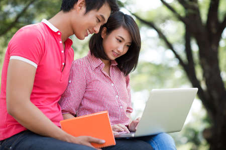 College friends doing homework together with the help of modern technologyの写真素材