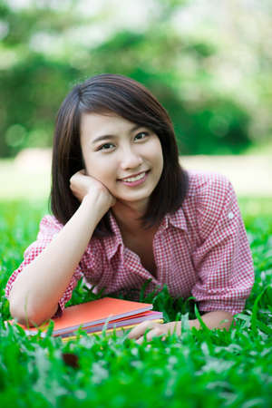 Vertical portrait of a lovely girl doing homework in the open airの写真素材