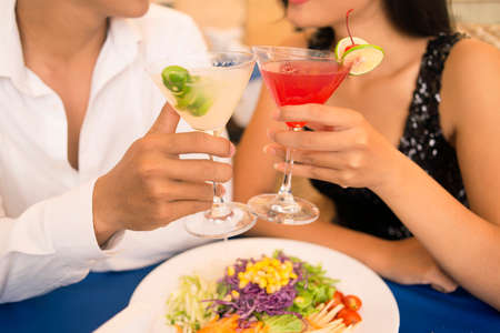 Couple clinking cocktails while having a romantic dinnerの写真素材