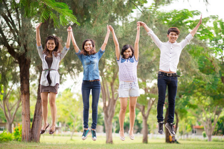 Four teenage friends jumping outdoors
