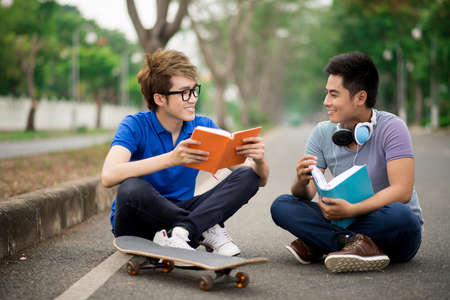 Teenagers reading books outdoors in the parkの写真素材