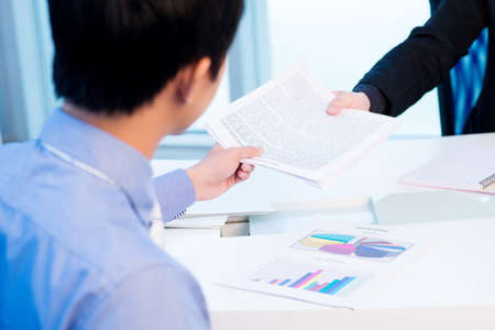 Colleagues passing a business document to each otherの写真素材