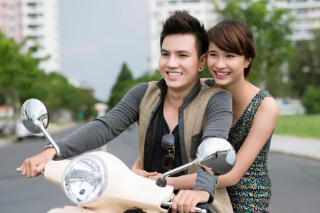 Girl and guy enjoying an urban scooter rideの写真素材