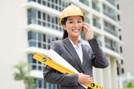 Female engineer consulting by phone right from the construction siteの写真素材
