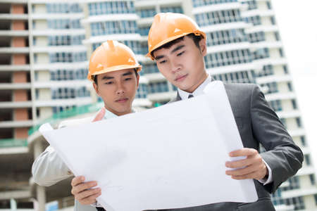 Serious engineers looking at the construction planの写真素材