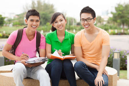 Portrait of three students sitting outdoors in breakの写真素材