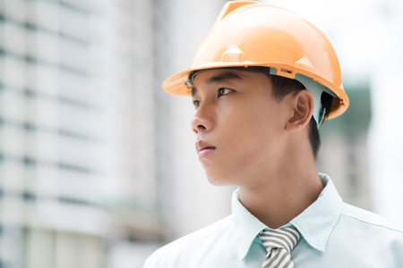 Close-up portrait of a young businessman in hardhat looking in future with confidenceの写真素材