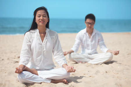 Young couple practicing yoga in summer environmentの写真素材