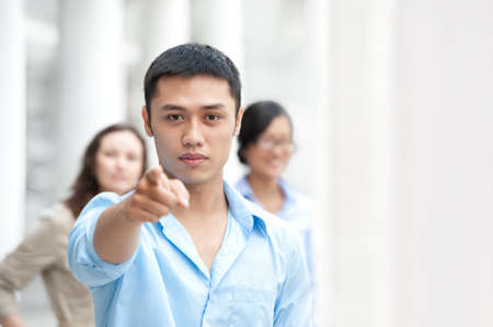 Young businessman pointing at you with his colleagues behindの写真素材