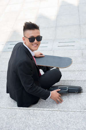 Vertical portrait of a business guy having skateboarding as a hobbyの写真素材