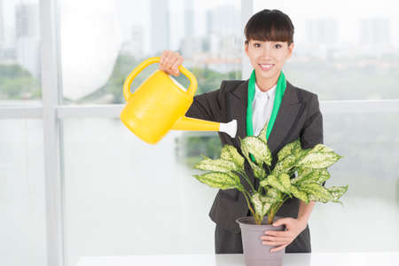 Portrait of a woman watering a plant with a watering-pot insideの写真素材