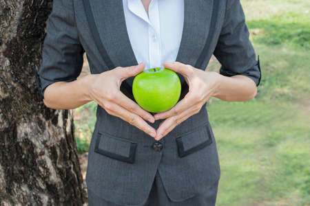 Close-up of female hands holding green apple outdoorsの写真素材