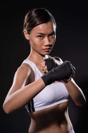 Vertical portrait of a female kick boxer in hand bandage against a grey backgroundの写真素材