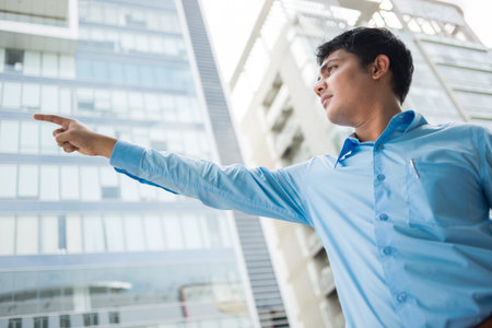 Serious young businessman showing direction in the cityの写真素材