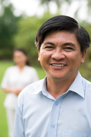 Close-up portrait of a handsome mature man smiling and posing on camera on the foregroundの写真素材