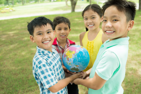 Portrait of smiling kids holding a globeの写真素材