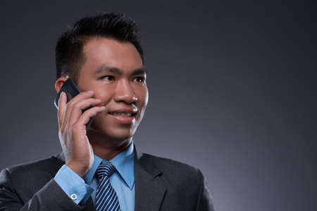 Close-up image of a businessman talking by cell phone isolated on greyの写真素材