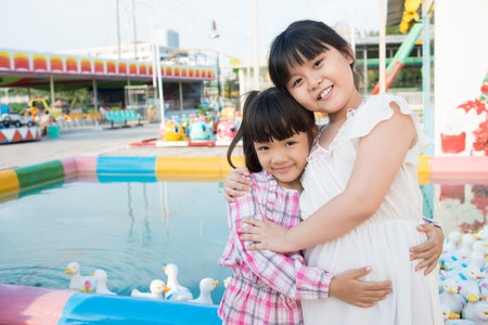 Portrait of two cuties hugging by the pool full of rubber ducksの写真素材