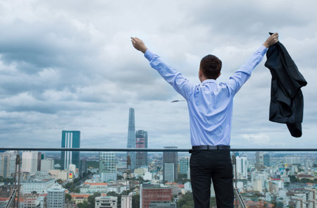 Back view of a young businessman having triumph standing outsideの写真素材