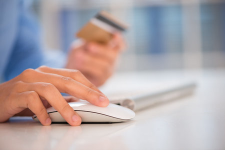 Close-shot of a human hand clicking a computer mouse on the workplace の写真素材