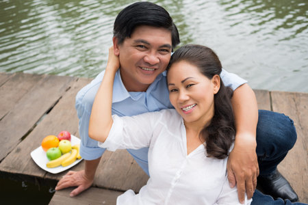 Close-up portrait of a happy mature couple resting on the riversideの写真素材