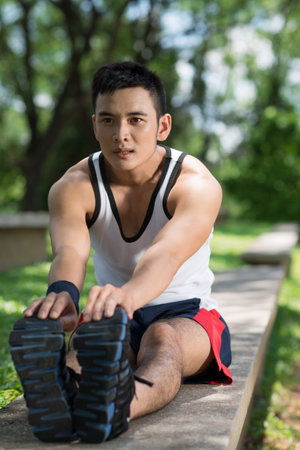 Vertical image of a sportsman stretching in the park