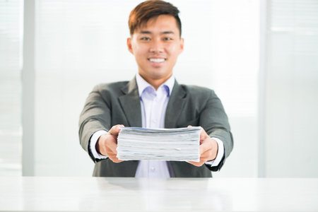 Portrait of a young businessman holding a heap of documents before deadline の写真素材