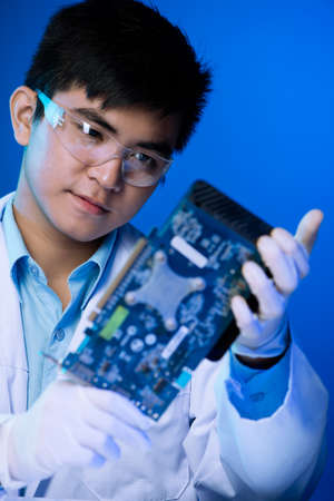 Vertical image of an electronic engineer working with a computer video card over a blue backgroundの写真素材