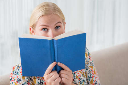 Frightened woman looking out of the bookの写真素材