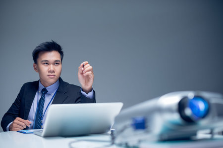 Isolated image of a young concentrated businessman pointing at something with the pen while working on the foreground の写真素材