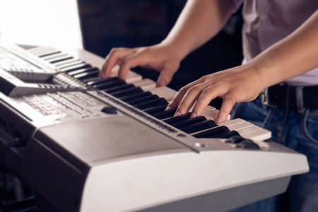 Close-up image of human hands playing the piano on the foregroundの写真素材