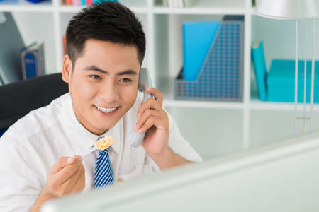 Positive business worker answering lunchtime callの写真素材